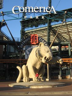 a large white bear statue sitting in front of a baseball stadium with the words comerica park on it