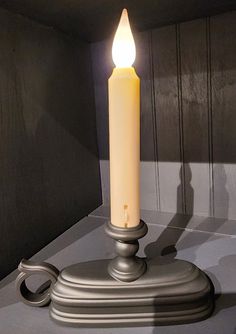 a lit candle sitting on top of a metal stand