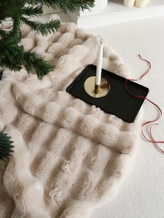 a candle is sitting on top of a fur rug next to a small christmas tree