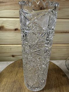 a clear glass vase sitting on top of a wooden table next to a wood paneled wall