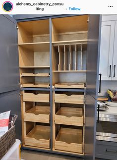 an empty cabinet in the middle of a kitchen with lots of drawers and shelves on each side