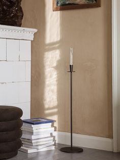 a candle is sitting on top of a stack of books in front of a fireplace