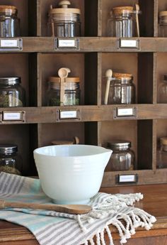 a white bowl sitting on top of a wooden table next to jars and spoons