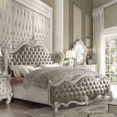 a white bed sitting in the middle of a bedroom next to a dresser and mirror