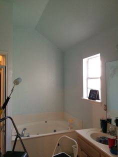 a bathroom with a tub, sink and mirror in it's corner next to a window