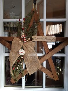 a wooden star with a christmas decoration hanging from it's side in front of a window