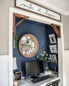 a desk with a computer on it in front of a blue wall and some pictures