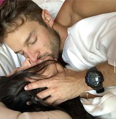 a man laying in bed with his head on the woman's shoulder while she sleeps next to him