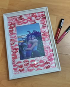 a photo frame with lipstick on it next to two pens