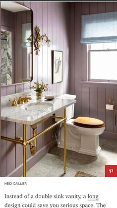 a bathroom with purple walls and marble counter tops, gold fixtures and a white toilet