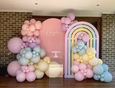 an arch is decorated with balloons and pastel colors