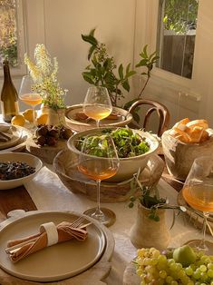 the table is set with wine, fruit and bread for an elegant dinner or brunch