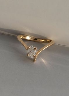 a yellow gold ring with a single diamond in the center on a plain surface,