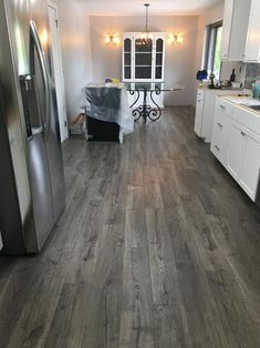 a kitchen with wood flooring and white cabinets in the background, an open door leads to a dining room