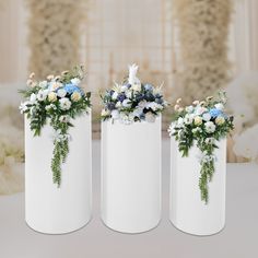 three white vases with blue and white flowers in them