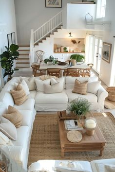 a living room filled with white furniture and lots of pillows on top of it's couches