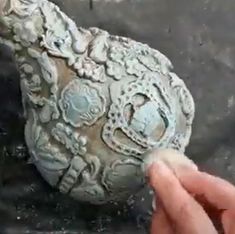 a person is holding a piece of pottery in their left hand and touching it with the other hand