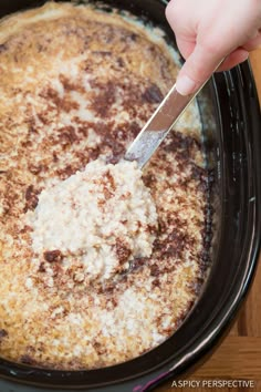 someone using a knife to cut food in the crock pot with cheese on top