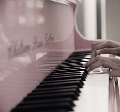 a person's hand on the keys of a pink piano, while they are playing it