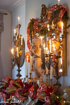 a christmas mantle with candles and ornaments on it in front of a mirror that is hanging from the wall