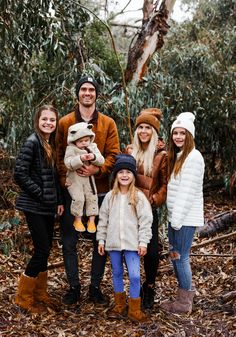 a group of people standing next to each other in front of trees and leaves on the ground