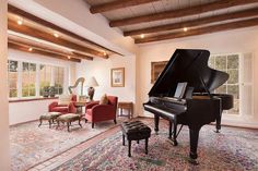 a grand piano in the middle of a living room with red chairs and rugs