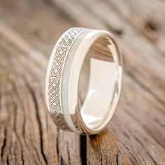 a wedding ring with an intricate design on the outside and inside, sitting on a wooden surface