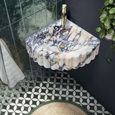 a marble sink in a bathroom next to a rug and potted plant on the floor