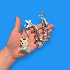 Bring some whimsy to your outfit with our Critter Bead Necklace, adorned with a charming Calico Critter. Each necklace is one-of-a-kind, handmade in Manchester, UK with varying colors and beads for a unique touch. Elastic thread and a clasp closure make it easy to wear. Playful Blue Adjustable Beaded Necklace, Whimsical Blue Pendant Jewelry, Cute Blue Necklace For Gift, Playful Adjustable Blue Beaded Necklace, Playful Handmade Adjustable Charm Necklaces, Blue Beaded Charm Necklaces With Round Beads, Whimsical Blue Necklace For Gifts, Playful Blue Jewelry For Jewelry Making, Whimsical Blue Necklace For Gift