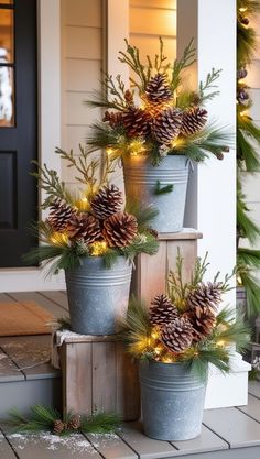 three potted plants with pine cones and lights in them on the front porch for christmas