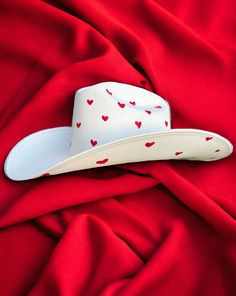 Darling features the most precious little red hearts adorning the crown and under the brim of a hard white canvas cowboy hat Proudly American Made. Our hats are manufactured in Mexico and details added by hand in Los Angeles, CA using the highest quality materials. SIZING S/M 19in-22.75in | 48cm-57.5cm L/XL 19.5in-23.25in | 49.5cm-59cm **Please allow up to 2 weeks for production and shipping.* If you need your order rushed, please send us an email. We can almost always accommodate rushed orders Custom White Fedora For Country Events, White Country Top Hat With Curved Brim, White Brimmed Country Top Hat, White Brimmed Country Style Top Hat, White Country Style Top Hat With Curved Brim, Country Style White Brimmed Top Hat, White Country Fedora For Festivals, White Country Style Fedora For Rodeo, Country Style White Fedora For Rodeo