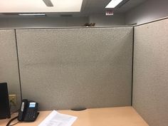 an office cubicle with a phone and telephone on the desk