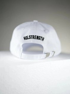 Whether it is a bad hair day or you just need to zone in and focus, we've got you covered with our custom Dad Hat. Solid 6-panel cap design. Duel embroidered HolStrength logo. Solid silver buckle with adjustable strap for custom fit. One-size fits most. HolStrength - Premium Christian Clothing White Adjustable Fitted Hat With Letter Print, Casual Adjustable Fitted Hat With Custom Logo, White Six-panel Dad Hat With Letter Print, Adjustable Hats With Custom Logo For Streetwear, Adjustable Fitted Cap With Custom Logo, White Adjustable Fitted Hat With Embroidered Logo, Adjustable White Baseball Cap, Adjustable White Dad Hat For Sports, Adjustable White Dad Hat For Sports Events