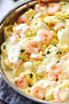 a pan filled with pasta covered in shrimp and cheese