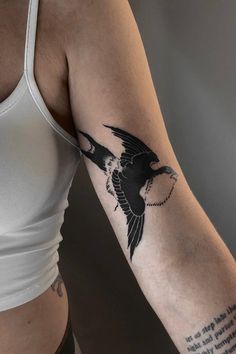 a woman's arm with a bird tattoo on the left side of her body