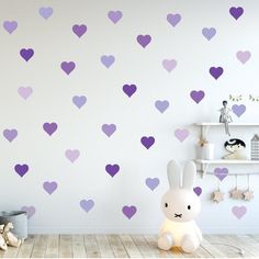 a room with purple hearts on the wall and a stuffed rabbit sitting in front of it