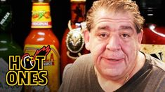 a man is standing in front of some hot sauces and ketchup bottles