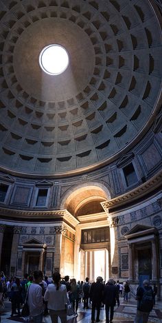 people are standing in the middle of a large room with a circular ceiling light above it