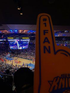 fans are watching a basketball game from the stands at an indoor arena with blue lights