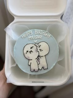 someone is holding up a birthday cake with an elephant on it in a plastic container