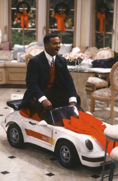 a man sitting on top of a toy car in a living room