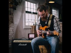 a man sitting down playing an electric guitar