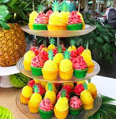 three tiered trays filled with cupcakes and pineapples