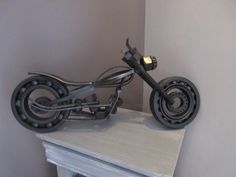 a motorcycle sculpture sitting on top of a white mantle next to a wall mounted clock