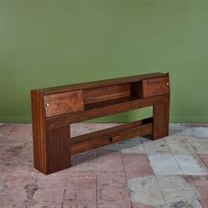 a wooden bench sitting on top of a tiled floor next to a green painted wall