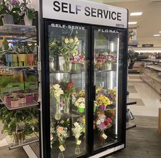 a display case filled with lots of flowers and plants in a store's flower section