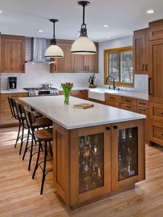 a large kitchen with wooden cabinets and white counter tops, along with bar stools