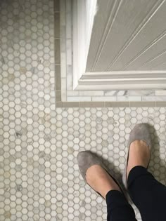 a person standing in front of a window with their feet up on the tile floor