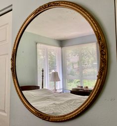 a round mirror hanging on the wall above a bed in a room with blue walls