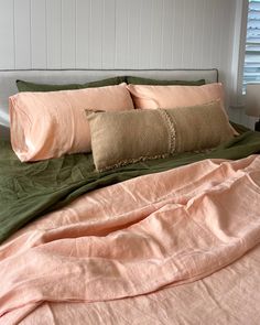 an unmade bed with two pillows on top of it and a blanket over the headboard